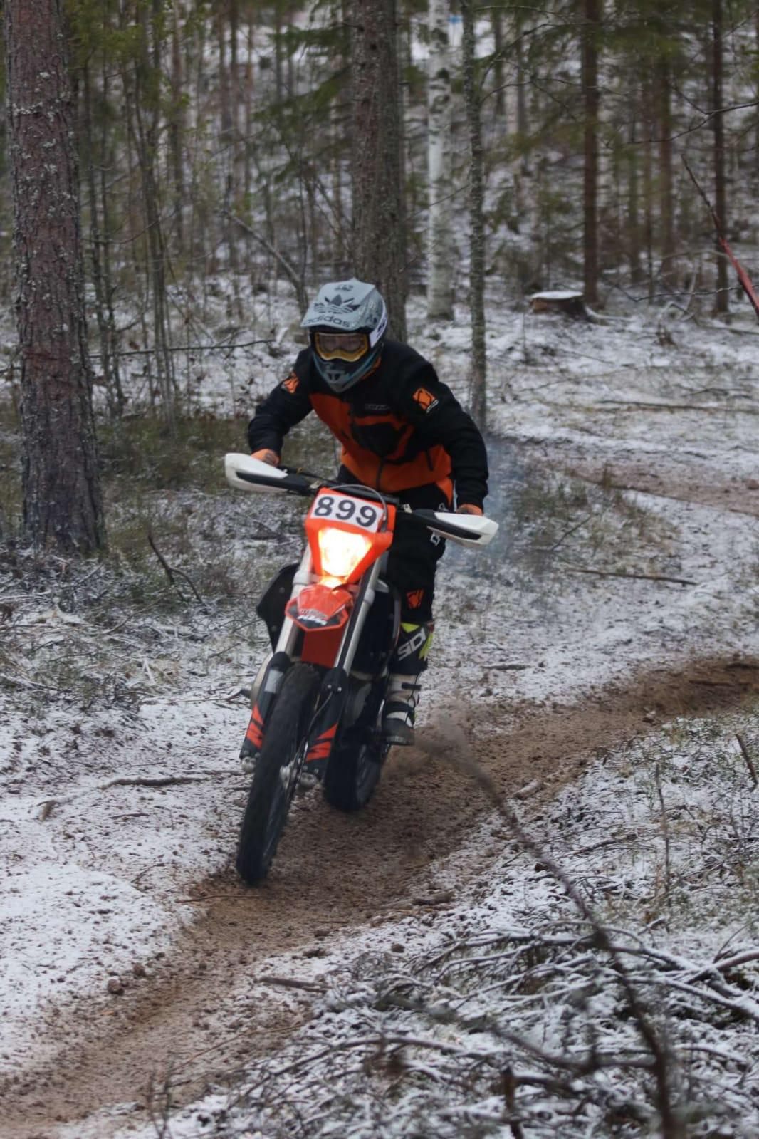 Enduroajaja lumisella metsäpolulla valot päällä