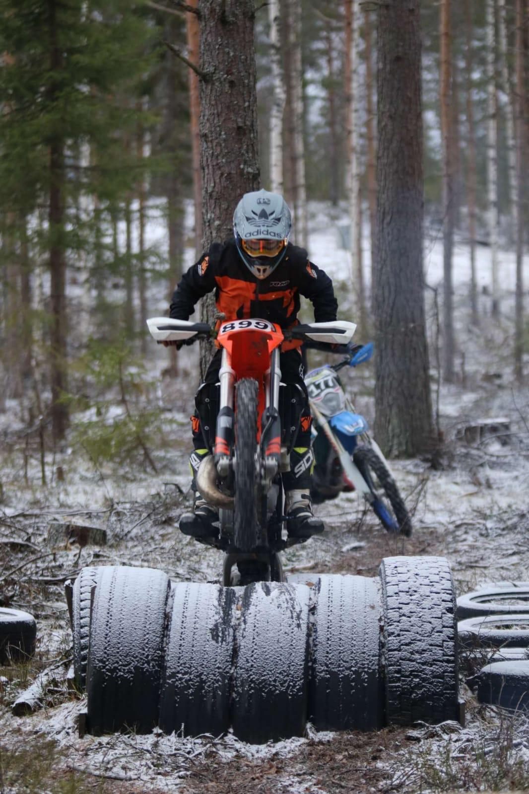Enduroajaja ylittämässä rengasestettä lumisessa metsässä