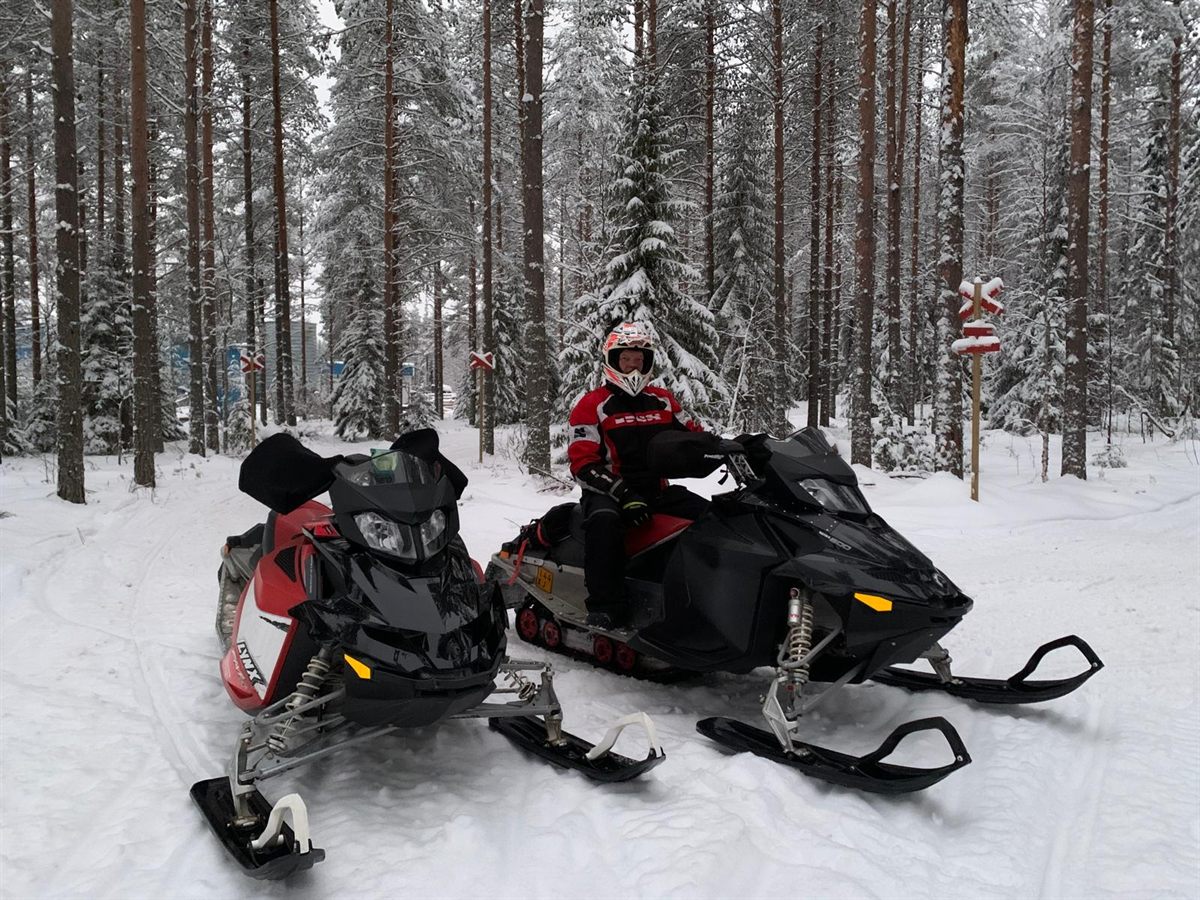 Moottorikelkat lumisessa metsässä