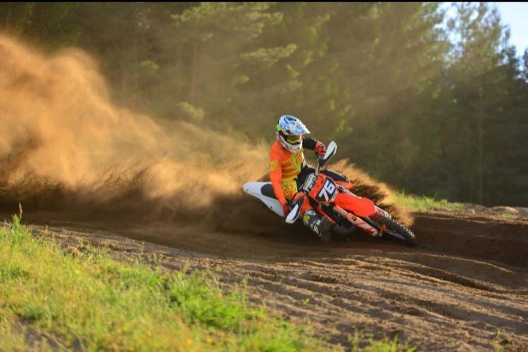 Motocross-ajaja kaarteessa pölypilvessä